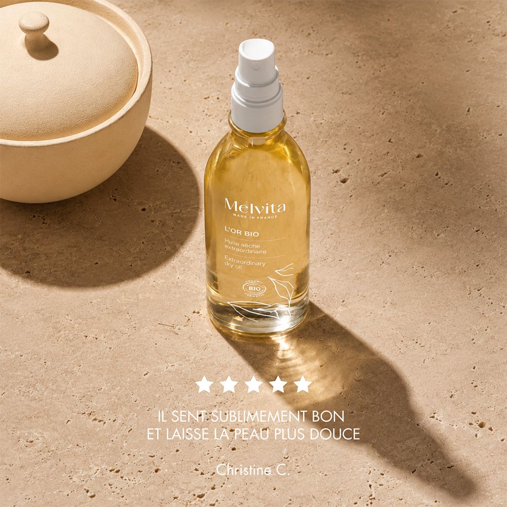 Bouteille Melvita L'Or Bio Extraordinary Dry Oil sur une dalle de pierre. Évaluation par étoiles et commentaire client.