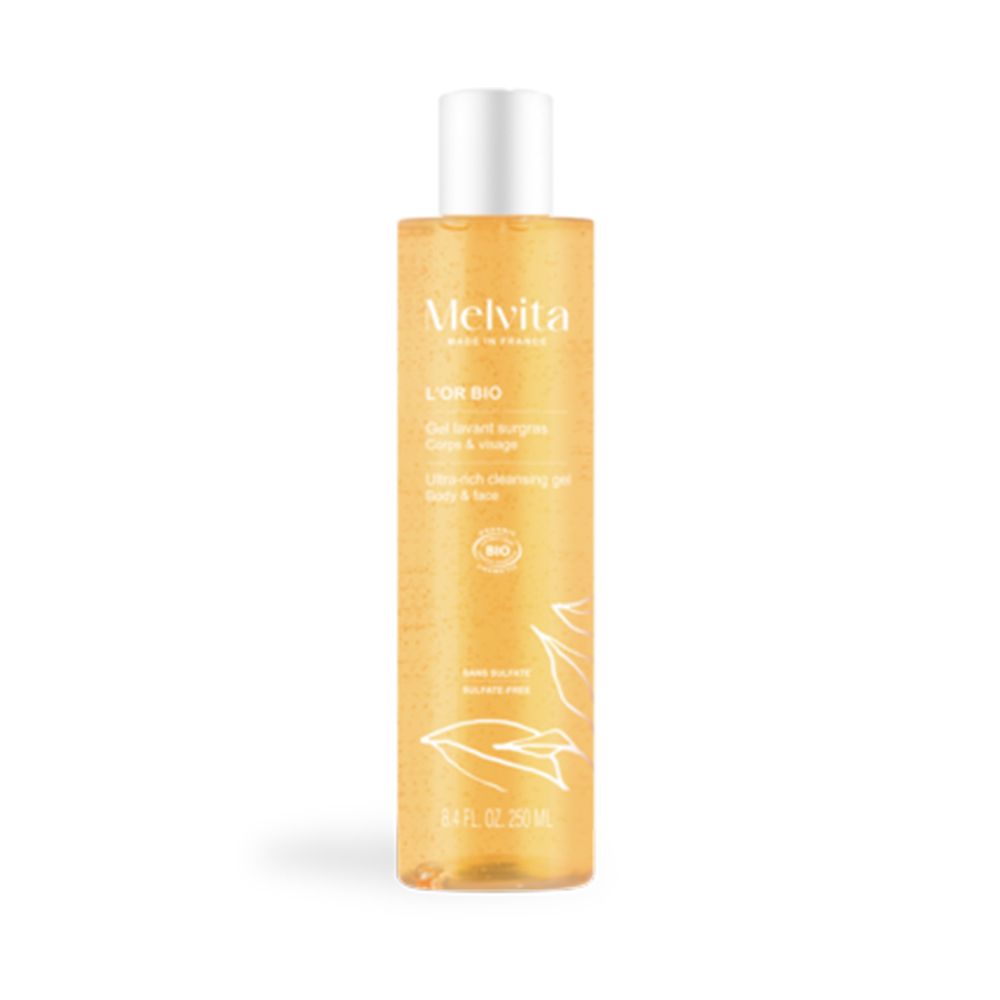Gel douche Melvita dans un flacon transparent avec bouchon blanc. Liquide doré avec motif de feuilles.