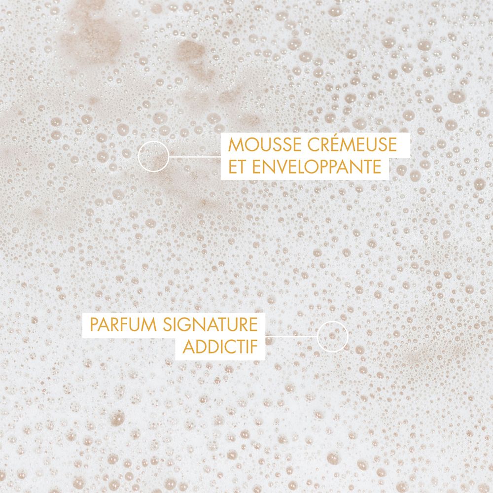 Gros plan de mousse riche avec des bulles. Texte : "MOUSSE CRÉMEUSE ET ENVELOPPANTE" et "PARFUM SIGNATURE ADDICTIF".