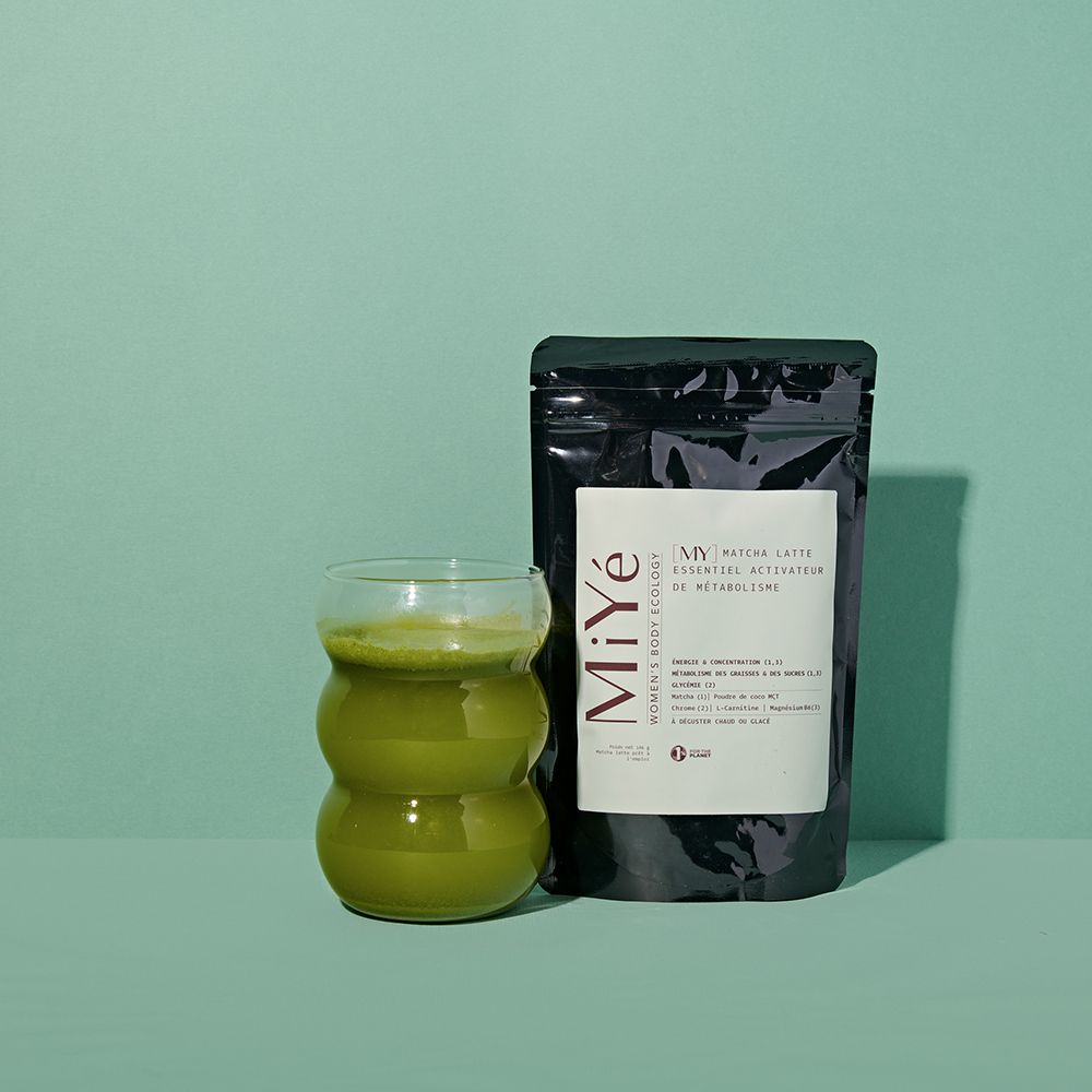 Sachet Miyé Matcha Latte à côté d'un verre contenant une boisson verte.