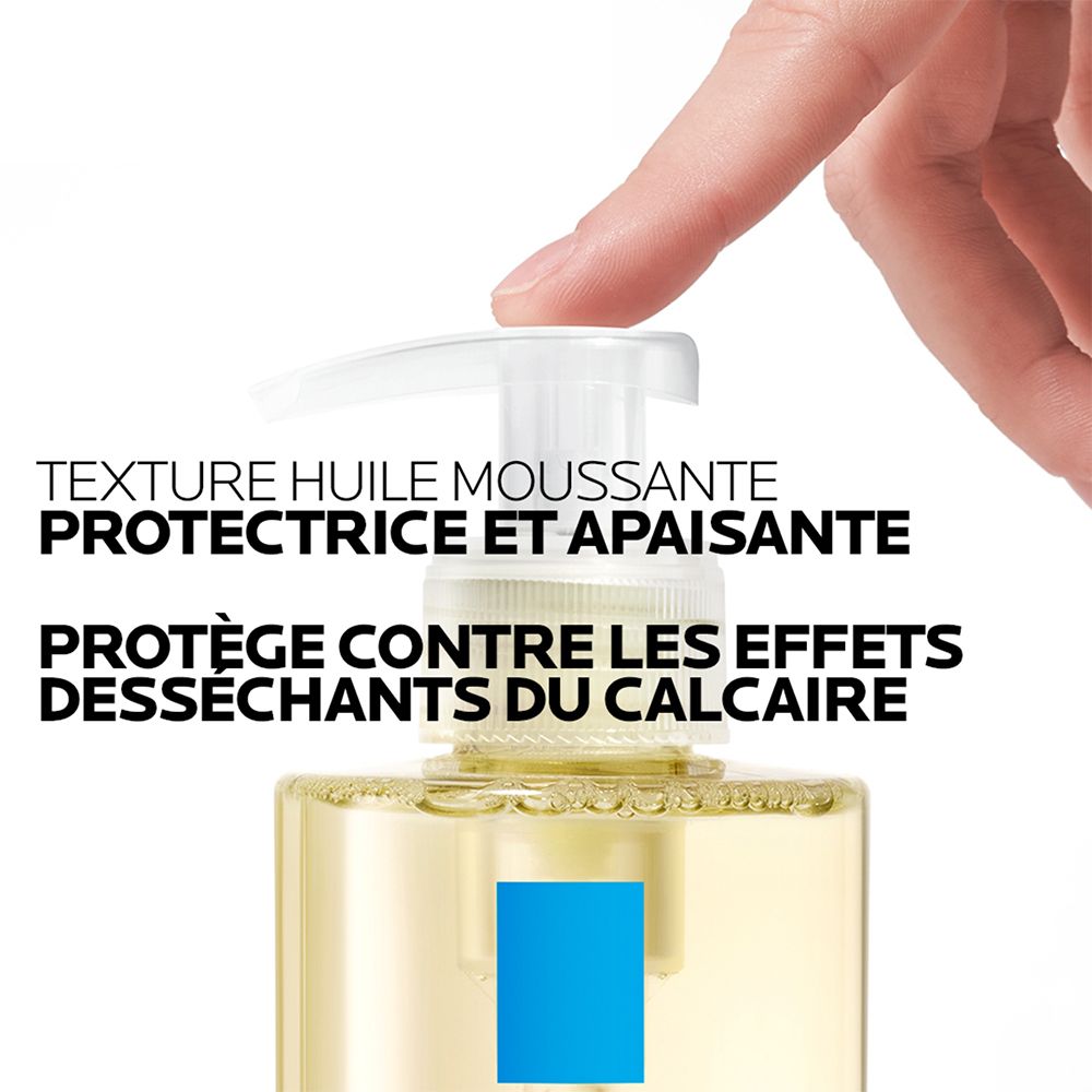 Flacon pompe avec huile jaune et logo carré bleu. Une main appuie sur la tête de pompe.