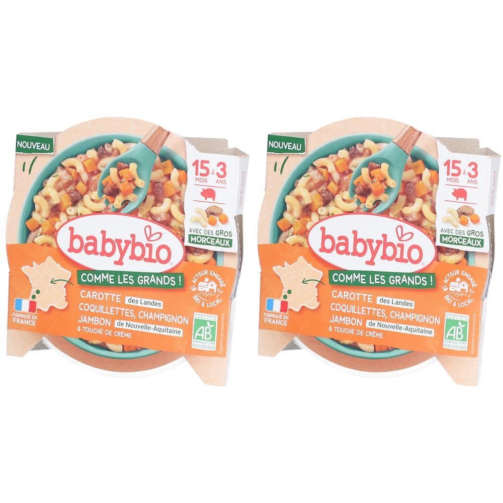 Deux barquettes de nourriture pour bébé Babybio. Inscription: Coquillettes Carotte Champignon Jambon. Avec label AB bio et drapeau français.