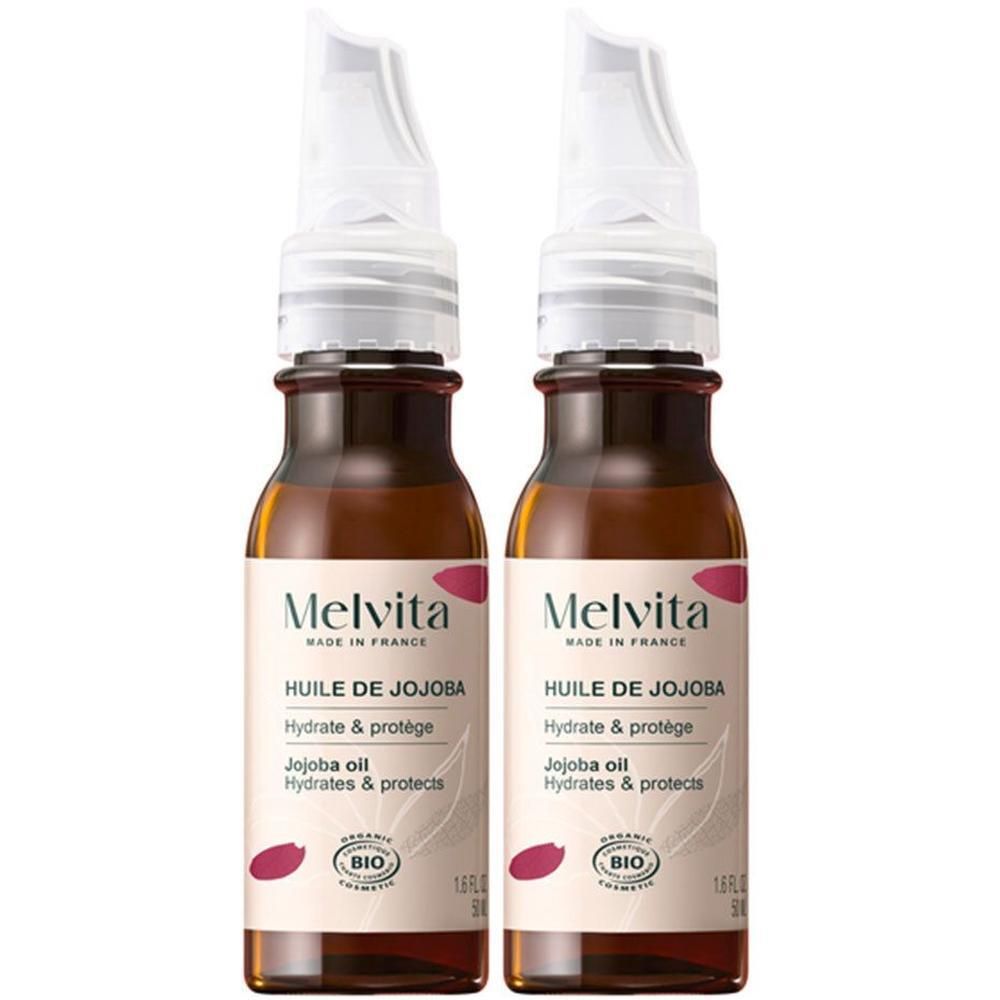 Deux flacons d'Huile de Jojoba Bio Melvita. Flacons en verre brun avec bouchon blanc et étiquette. Certification bio.