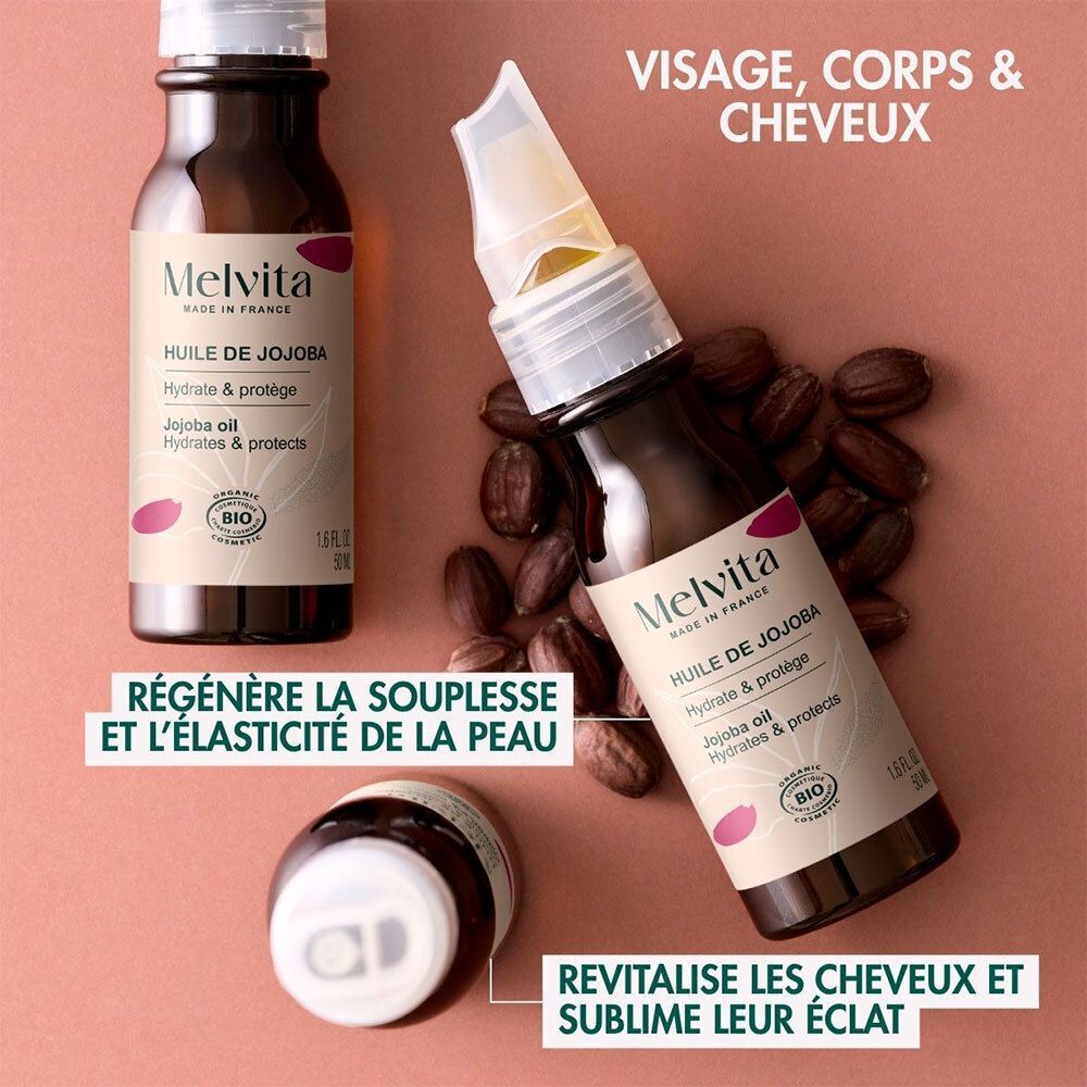 Trois flacons d'Huile de Jojoba Bio Melvita. Flacons en verre brun, bouchon blanc et étiquette. Texte: Visage, corps, cheveux.