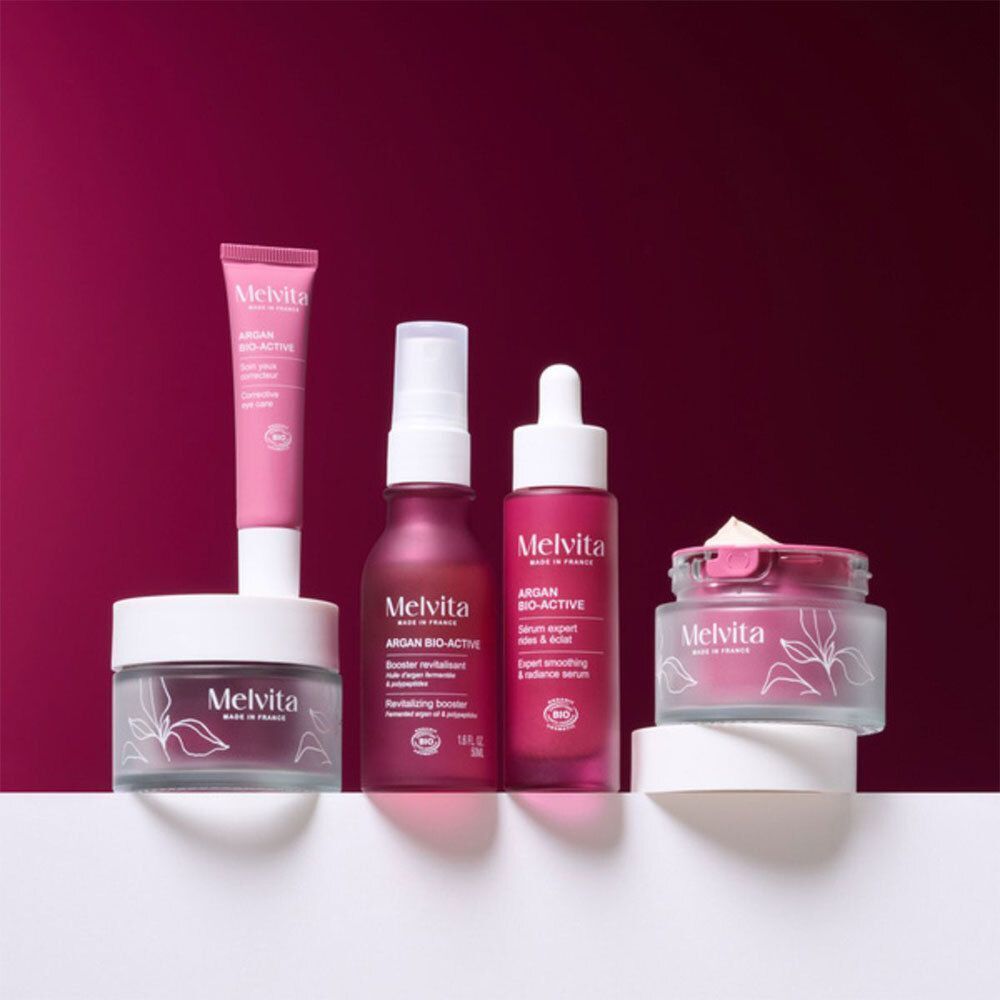 Plusieurs produits cosmétiques. Texte: Melvita Argan Bio-Active. Crèmes, sérum, crème yeux, flacon.