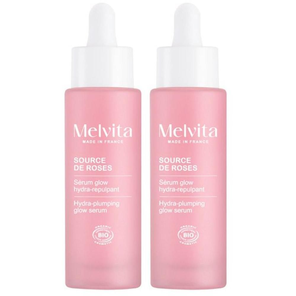 Deux flacons roses avec bouchon blanc et pipette. Inscription: Melvita, Source de Roses, Sérum glow hydra-repulpant, Bio.