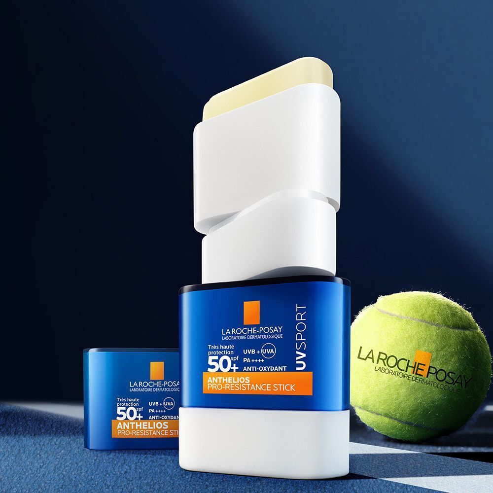 Stick solaire partiellement ouvert, à côté d'une balle de tennis. Inscription: Anthelios UVSport Stick Pro-Resistance SPF50+. Marque La Roche-Posay.