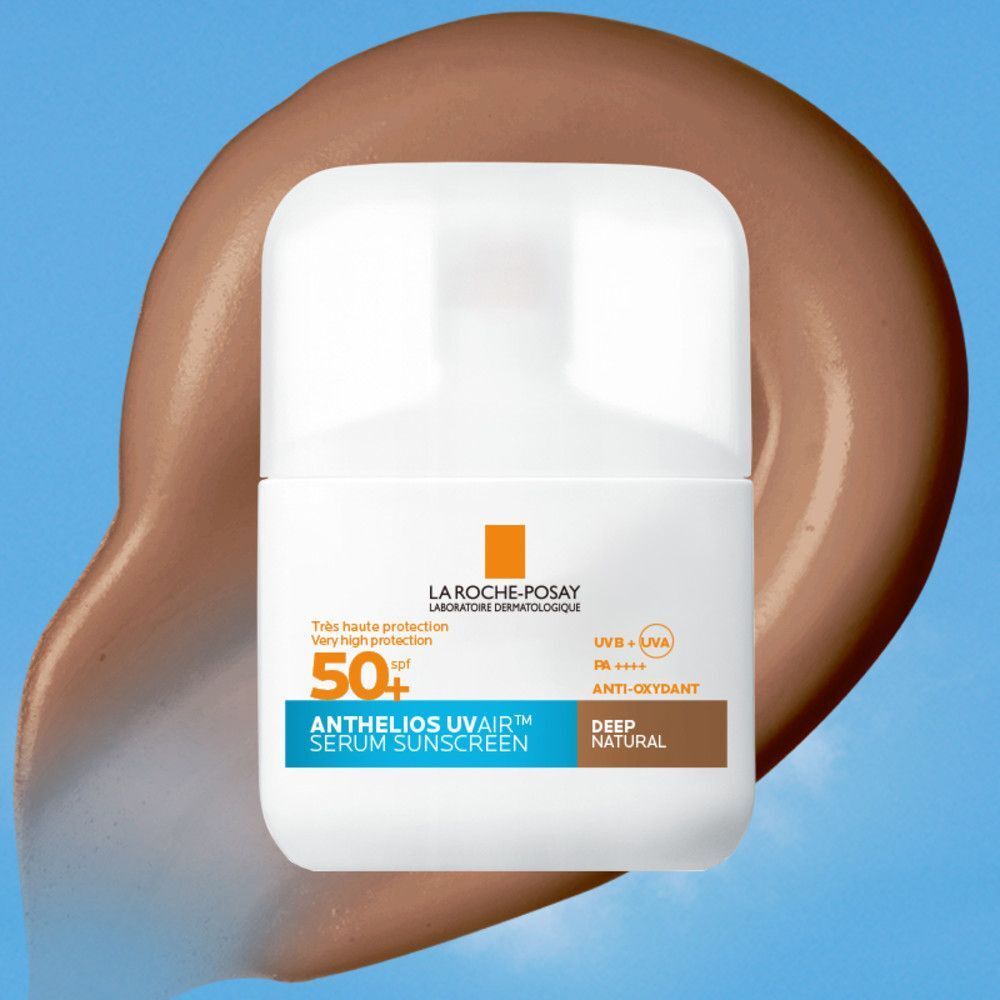 Flacon blanc avec bouchon blanc sur fond marron. Inscription: La Roche-Posay, Anthelios UVAir Serum Sunscreen SPF50+, Deep Natural.