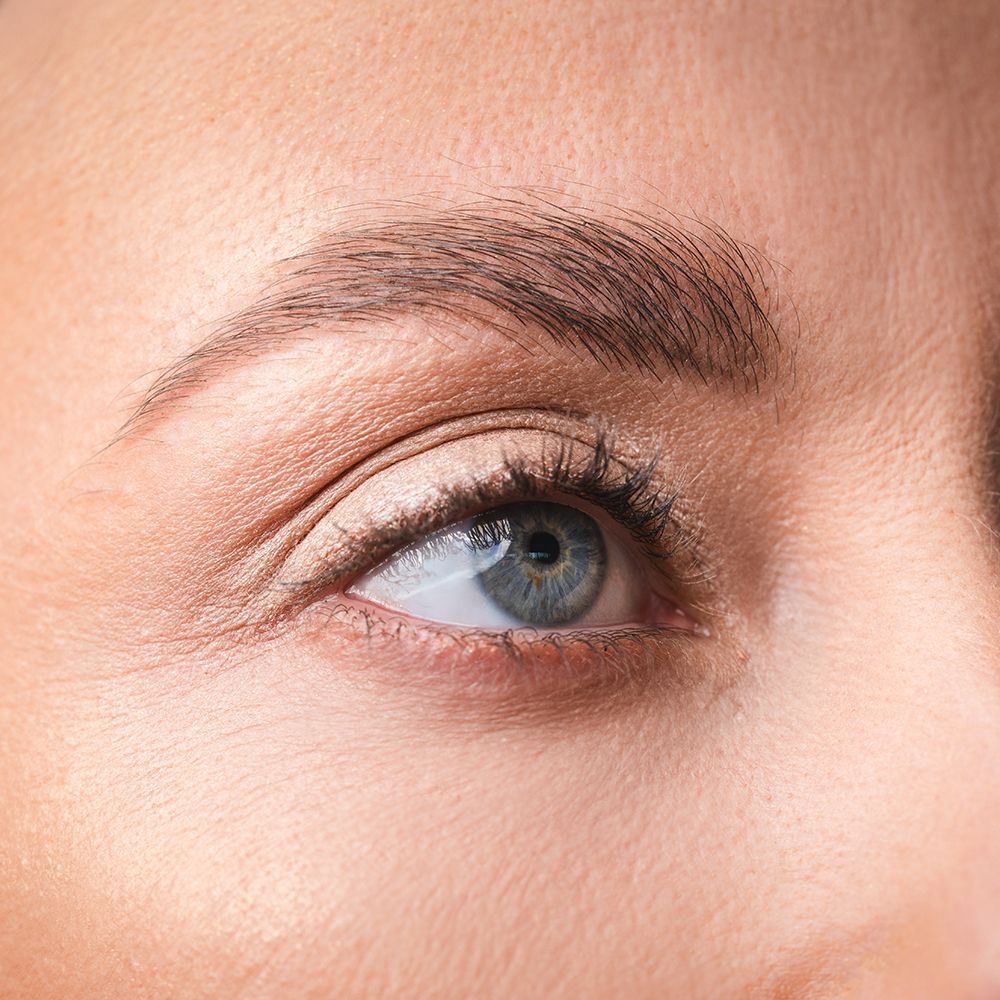 Gros plan d'un œil avec du mascara brun appliqué.