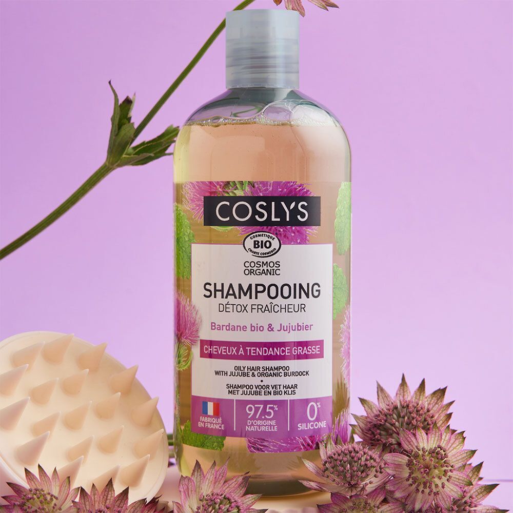 Flacon de shampooing avec étiquette. Texte: COSLYS, SHAMPOOING, DÉTOX FRAÎCHEUR. Certification bio. Avec brosse et fleurs.