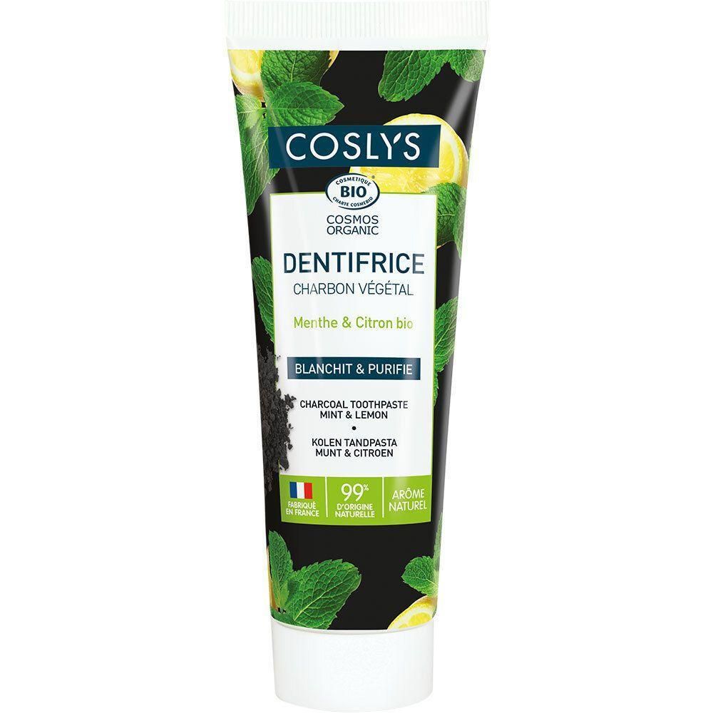 Tube de dentifrice COSLYS BIO, charbon végétal, menthe & citron. Fond noir avec feuilles de menthe et citrons. 99% d'ingrédients naturels.