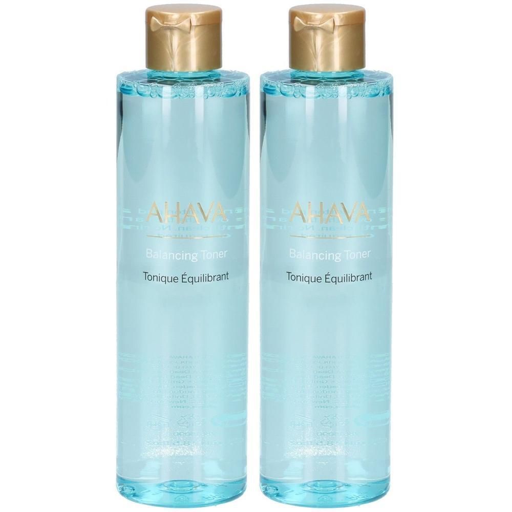 Deux flacons de tonique équilibrant AHAVA. Flacons cylindriques transparents avec bouchons dorés. Inscription : AHAVA, Balancing Toner, Tonique Équilibrant.
