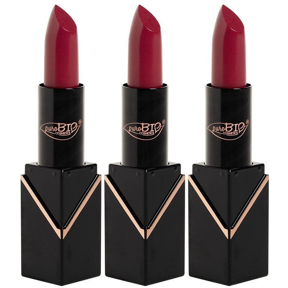 Trois rouges à lèvres fuchsia semi-mat. Tubes noirs avec détails dorés et logo "puroBIO cosmetics" visible.