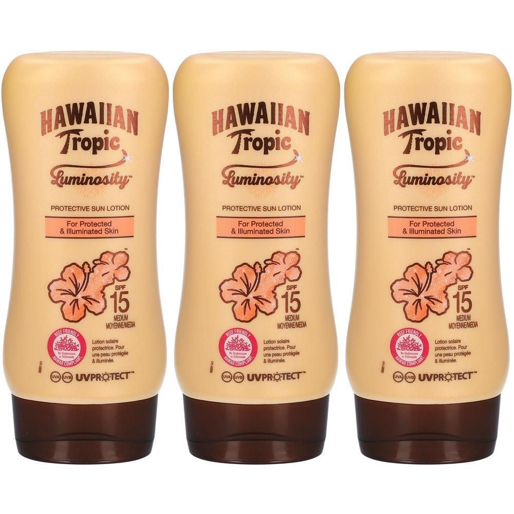 Trois flacons de lotion solaire Hawaiian Tropic Luminosity. Flacons beiges avec bouchons marron. Inscription : SPF 15.