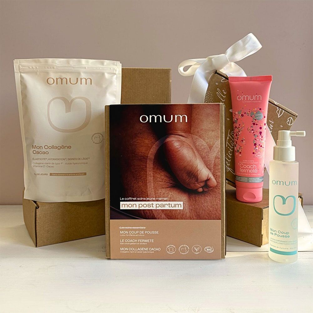 Coffret Post-Partum Omum : boîte en carton avec trois soins, empilés sur des cartons. Tube rose, flacon pompe, sachet beige.
