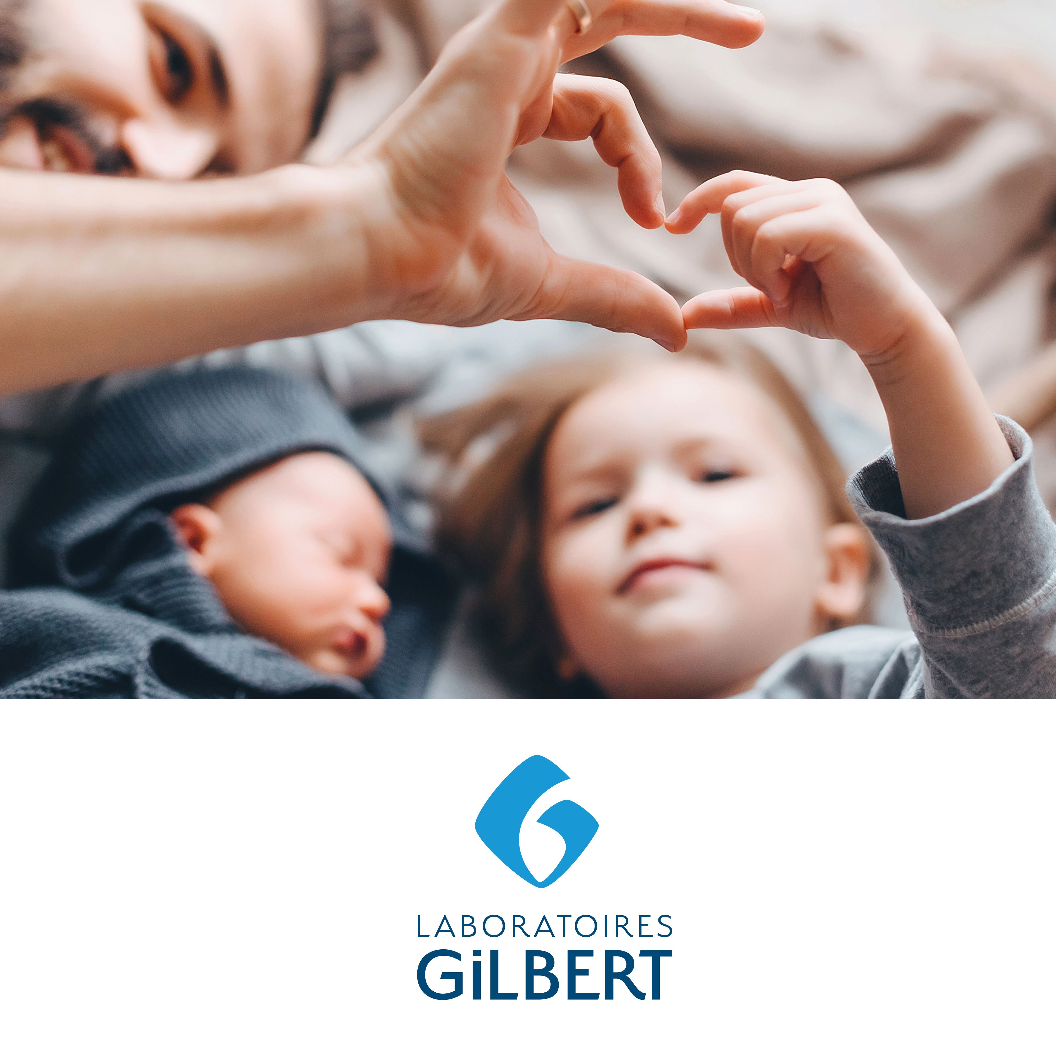 Famille formant un cœur avec les mains. Bébé et enfant en arrière-plan. Logo Laboratoires Gilbert.