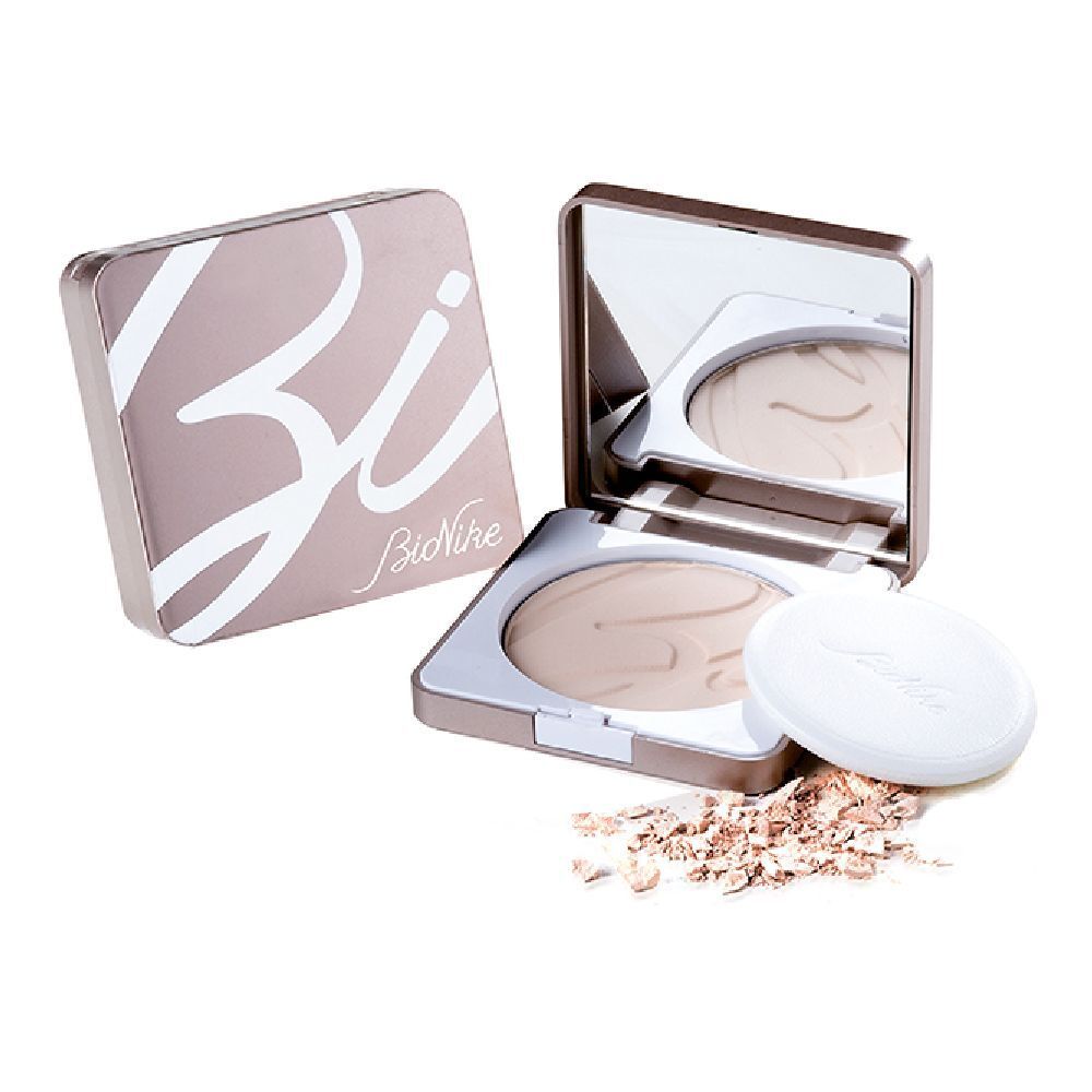 Poudre compacte avec miroir et applicateur. Boîte avec inscription. Poudre éparpillée à côté.