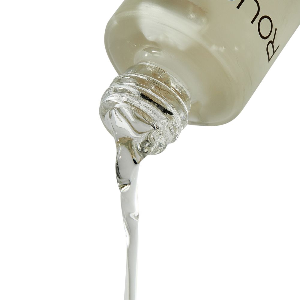 Liquide s'écoulant d'un flacon. Liquide clair et visqueux. Col du flacon avec bouchon argenté.