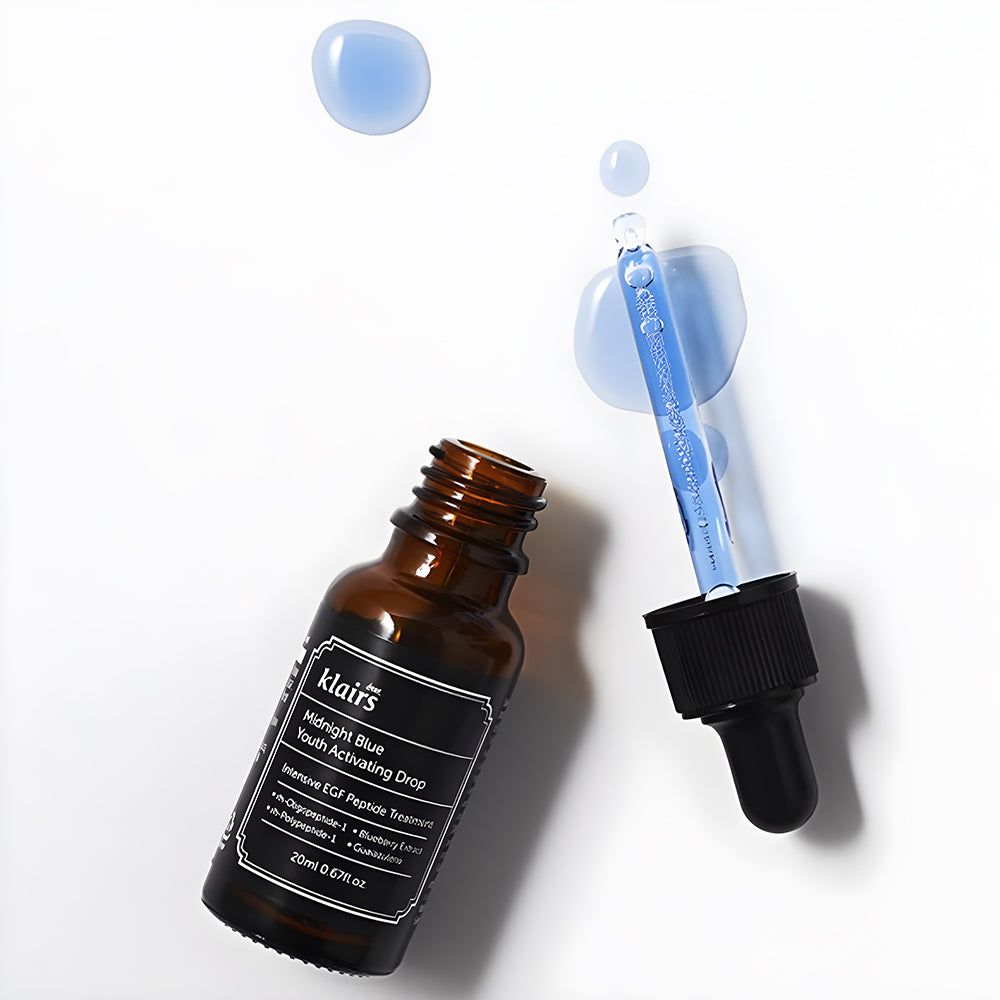 Flacon en verre brun avec étiquette noire et pipette. Liquide bleu et gouttes à côté. Nom du produit visible.