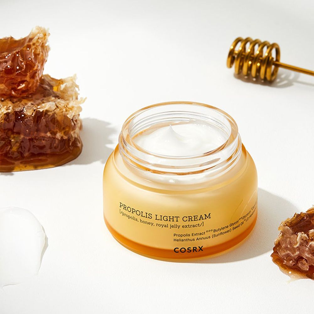 Crème légère Propolis COSRX dans un pot en verre avec des rayons de miel et un agitateur de miel.