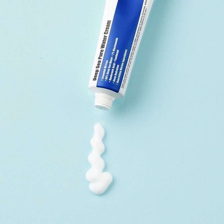 Crème blanche sortant d'un tube. Inscription : Deep Sea Pure Water Cream. Tube bleu et blanc, le produit est pressé.