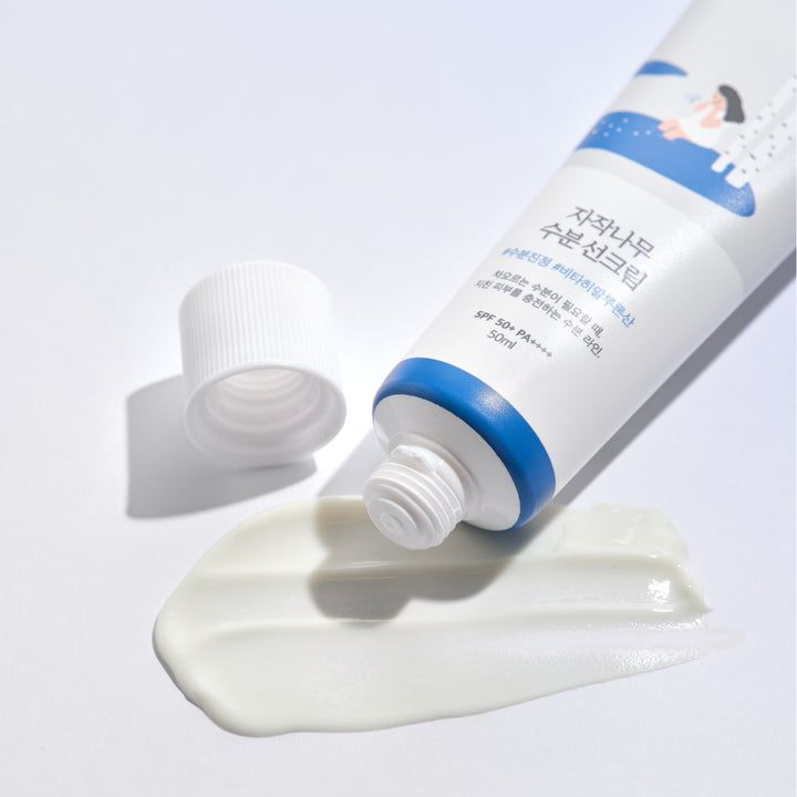 Tube de crème solaire appliqué et son bouchon ouvert.