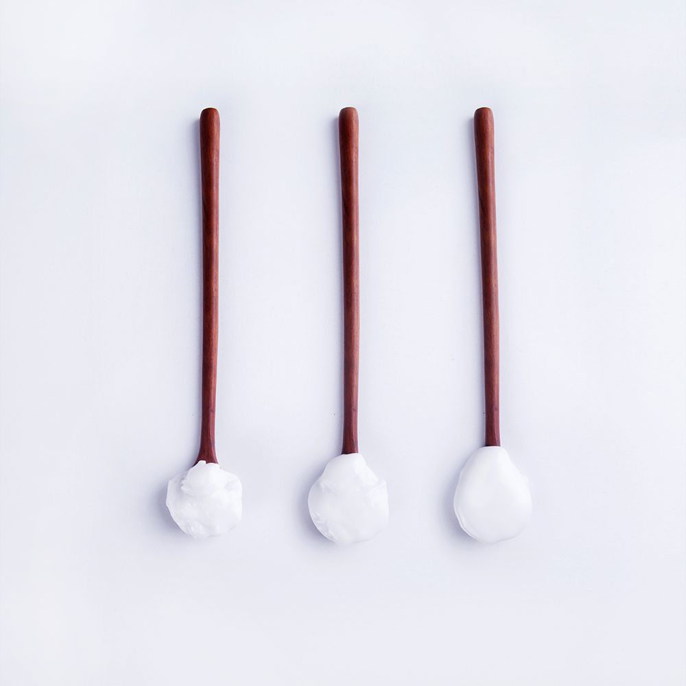 Trois spatules en bois avec des embouts blancs recouverts d'une crème blanche.