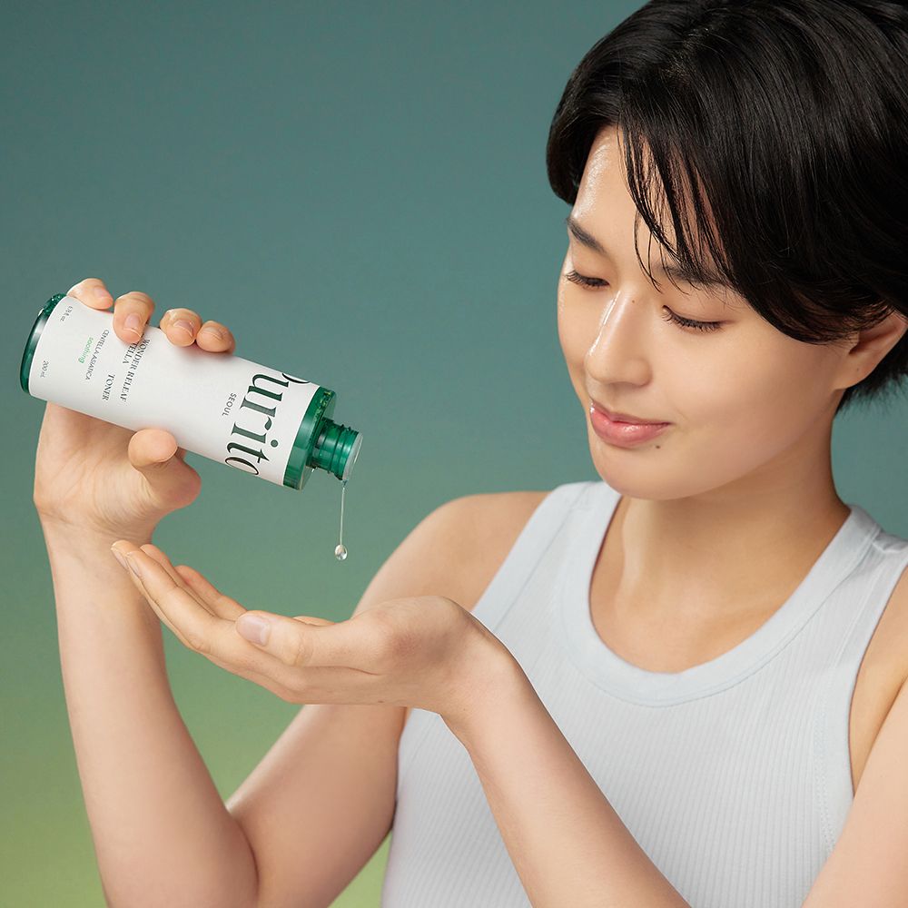 Une femme tient une bouteille. Le produit coule sur sa paume. Le produit est blanc et vert.