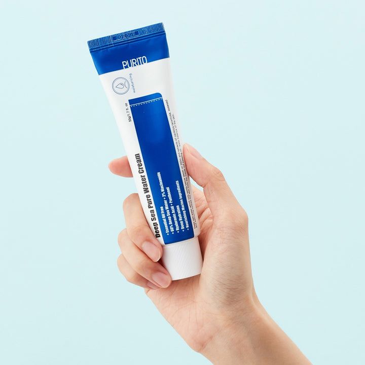 Une main tient un tube. Inscription : Deep Sea Pure Water Cream. Tube bleu et blanc, marque PURITO, logo poisson.
