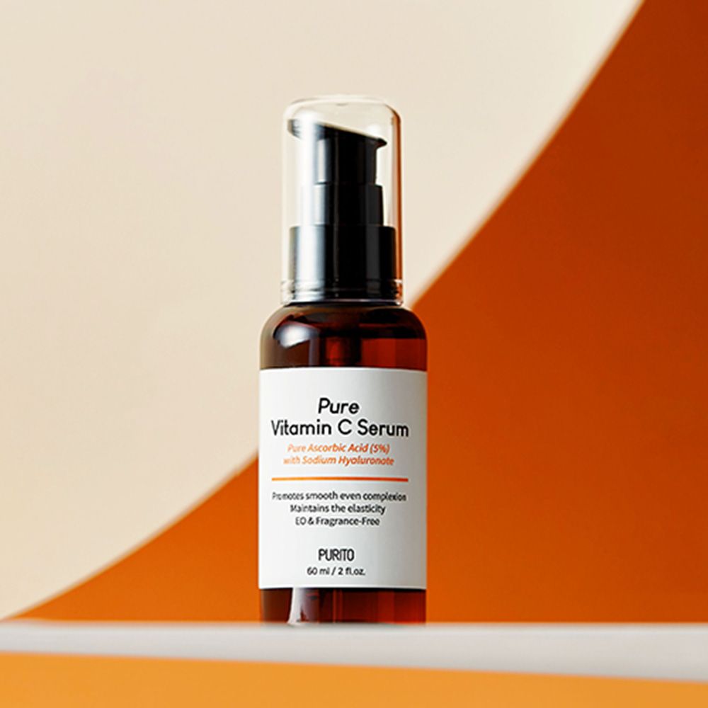 Flacon en verre brun avec pompe noire. Inscription : Pure Vitamin C Serum. Fond orange.